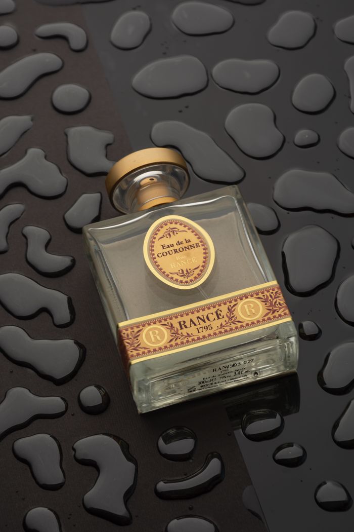 Close-up of a luxury perfume bottle on a textured wet surface, showcasing elegance and style.