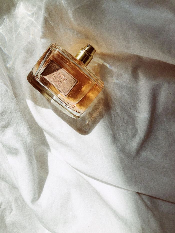 services-01 A luxurious perfume bottle resting on white fabric, illuminated by gentle sunlight.